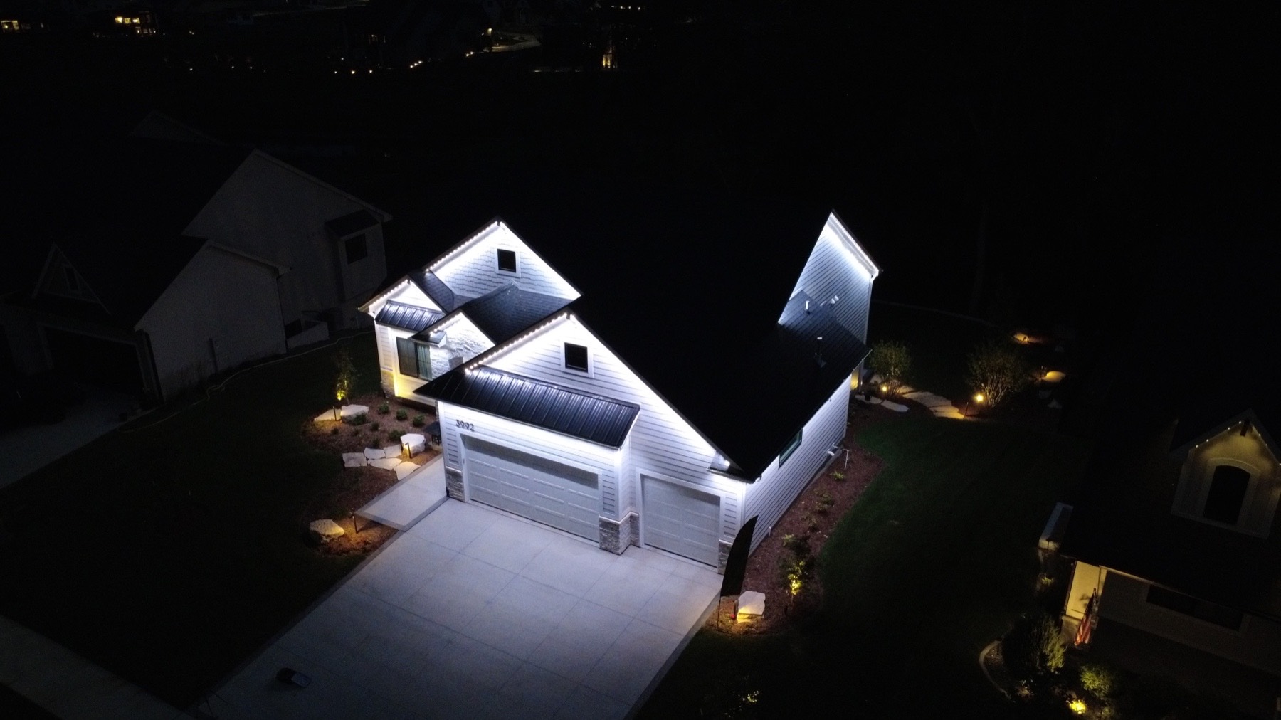 Aerial night view of a house outlined in permanent white lighting